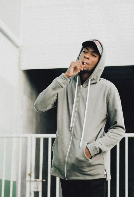 a man in a hoodie talking on a cell phone, an album cover, by Bascove, unsplash, lyco art, gray hoodie, full body! shot, dr dre, dressed in a gray