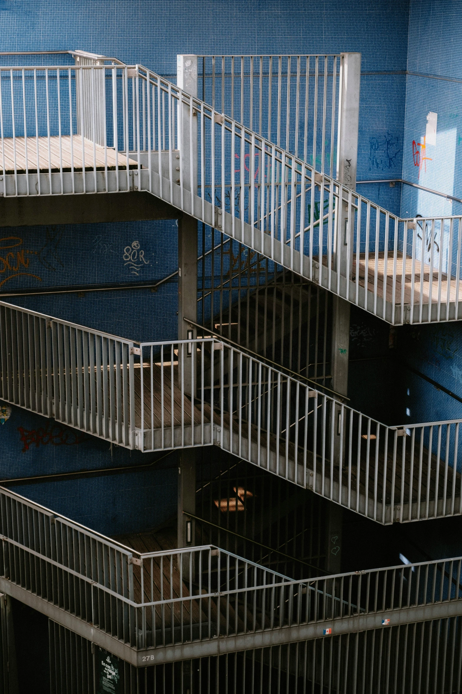 a man riding a skateboard down a flight of stairs, inspired by Elsa Bleda, pexels contest winner, graffiti, blue metal, apartment complex made of tubes, high angle vertical, blue gray