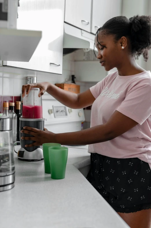 a woman is making a smoothie in a blender, pexels contest winner, renaissance, african american young woman, pink, low quality photo, robotic prosthetic arm