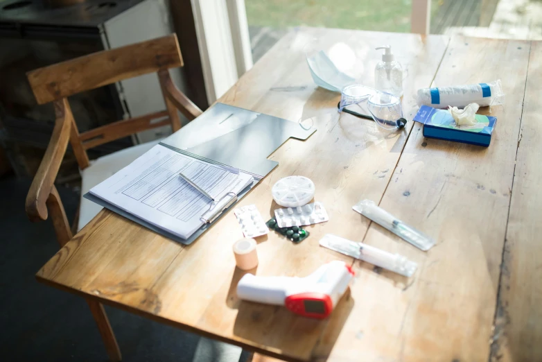 a wooden table with a bunch of items on it, by Jessie Algie, pexels, medical research facility, trying to study, syringes, sitting at table