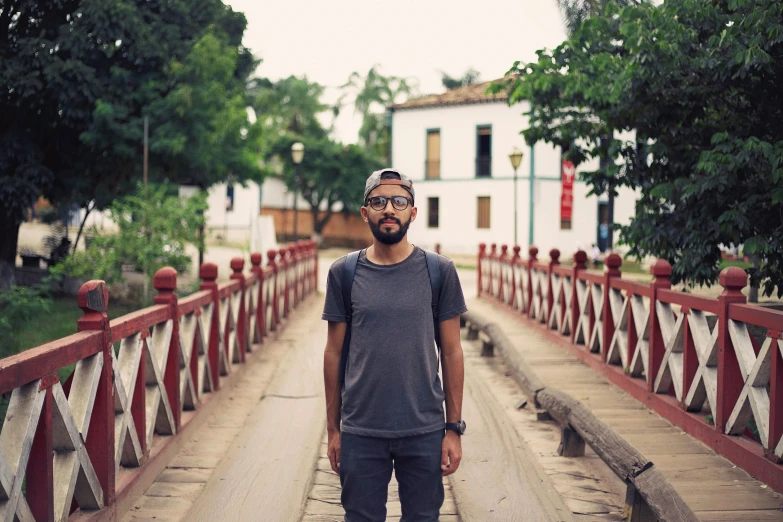a man standing on a bridge with a skateboard, a picture, inspired by Nathan Oliveira, trees in the background, shipibo, looking straight to camera, profile image