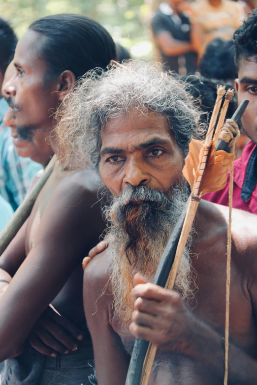 a group of men sitting next to each other, pexels contest winner, bengal school of art, holding a bow and arrow, grey beard, songlines, crowd of longhairs