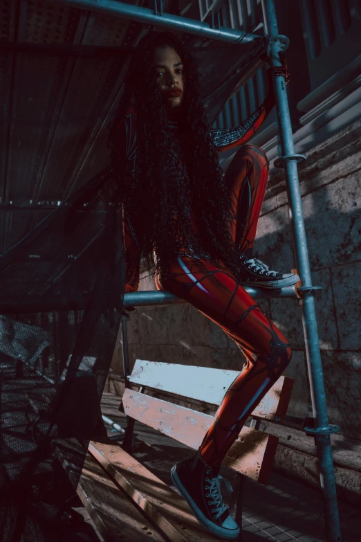 a woman sitting on a scaffolding in a dark room, afrofuturism, red and black suit, very long black/red hair, instagram photo, full body x-force outfit