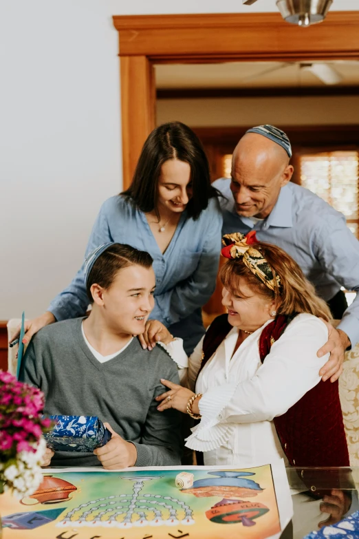 a group of people standing around a table with a cake, with a kid, someone in home sits in bed, israel, comforting