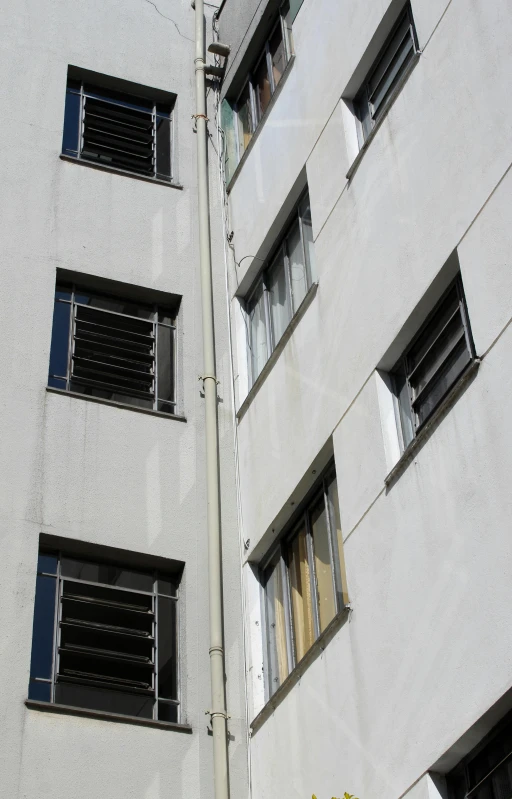 a tall white building with lots of windows, flickr, bauhaus, arson, metal shutter, window ( city ), low quality photo