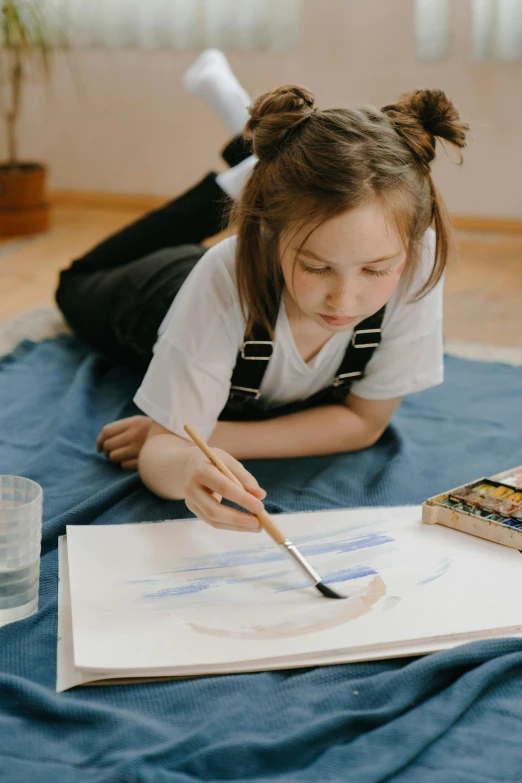 a little girl laying on top of a blue blanket, a watercolor painting, inspired by artist, pexels contest winner, analytical art, holding a paintbrush, girl wearing uniform, minimalistic painting, mate painting