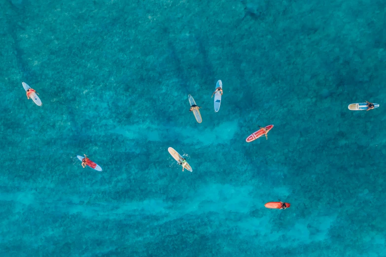 a group of people riding surfboards on top of a body of water, by Emma Andijewska, pexels contest winner, top down photo at 45 degrees, vivid hues, caribbean, small canoes