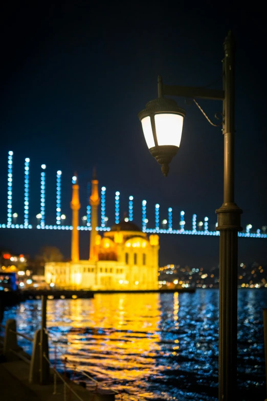 a street light sitting next to a body of water, inspired by Osman Hamdi Bey, hurufiyya, bridge, promo image, harbor, holiday