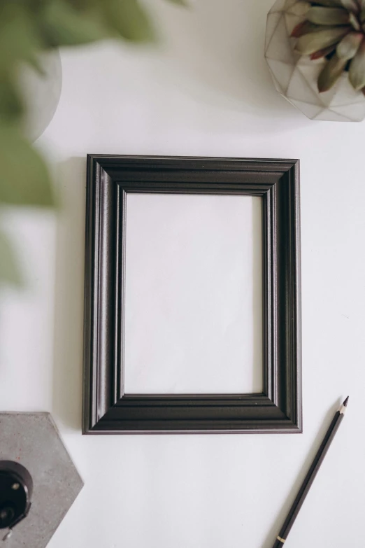 a black picture frame sitting on top of a white table, visual art, full product shot, craft, wall art, dark photo