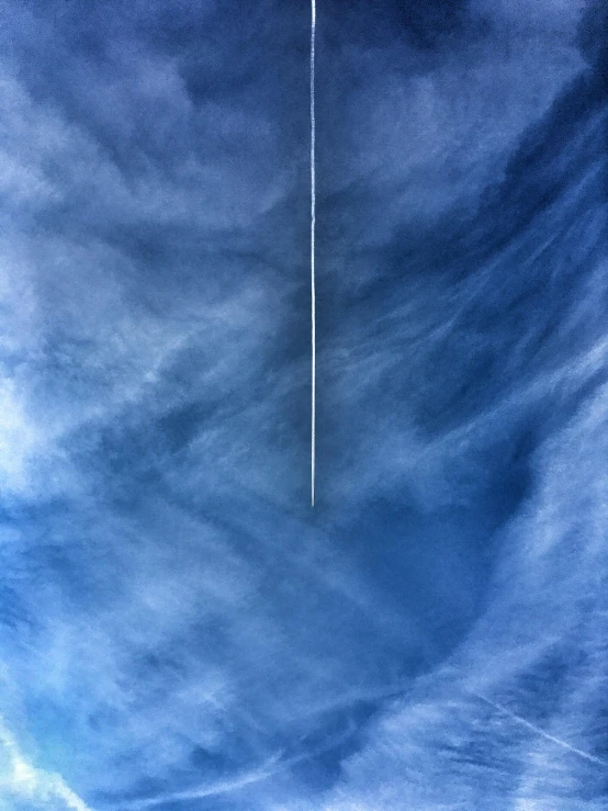 a jet flying through a cloudy blue sky, by Jan Tengnagel, postminimalism, single long stick, today\'s featured photograph 4k, high angle vertical, streaks