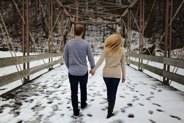 a man and a woman walking across a snow covered bridge, by Lucia Peka, pexels, renaissance, blonde, back, holding close, single