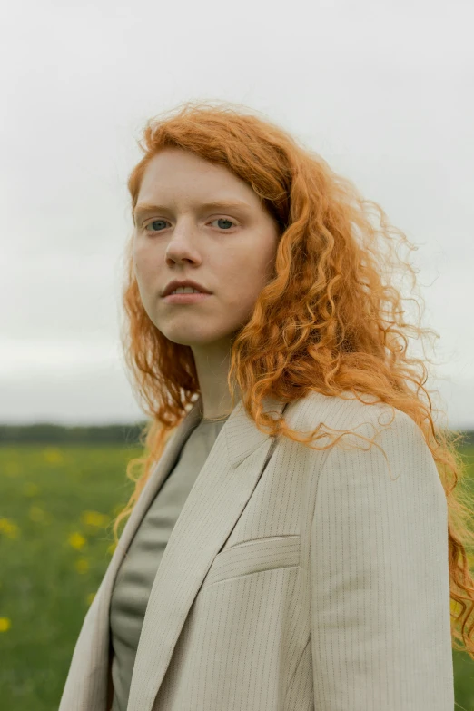 a woman with red hair standing in a field, an album cover, by Lasar Segall, in style of alasdair mclellan, hyperrealistic image, taken in 2022, portrait n - 9