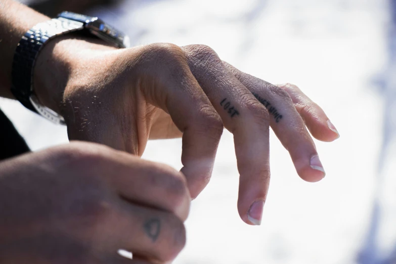 a close up of a person's hand with a wrist tattoo, a tattoo, by Daniel Lieske, unsplash, realism, point break, background image, shirtless biden with tatoos, oceanside