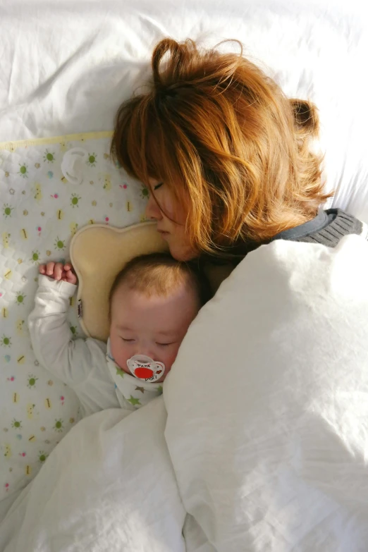 a woman laying in bed with a baby, head-to-shoulder, soft and warm, melting, head down