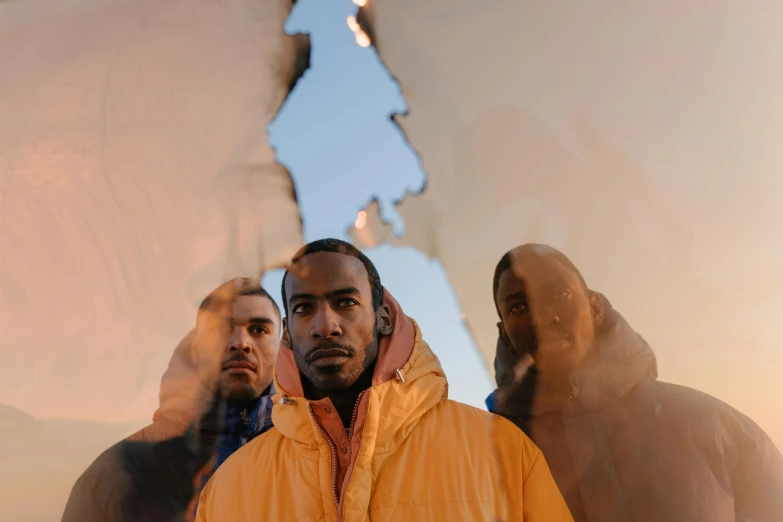 a group of men standing next to each other, an album cover, by artist, pexels contest winner, orange reflective puffy coat, looking up at camera, riyahd cassiem, high snow