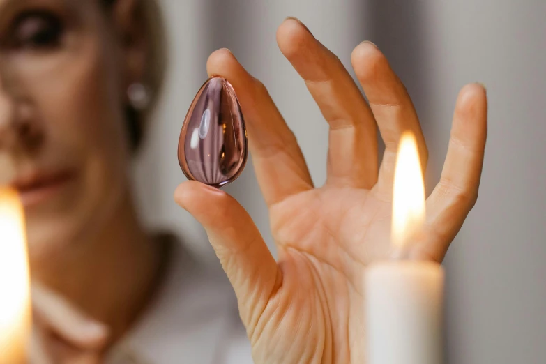 a close up of a person holding a candle, healing pods, purple, lightweight, mirror eye implants