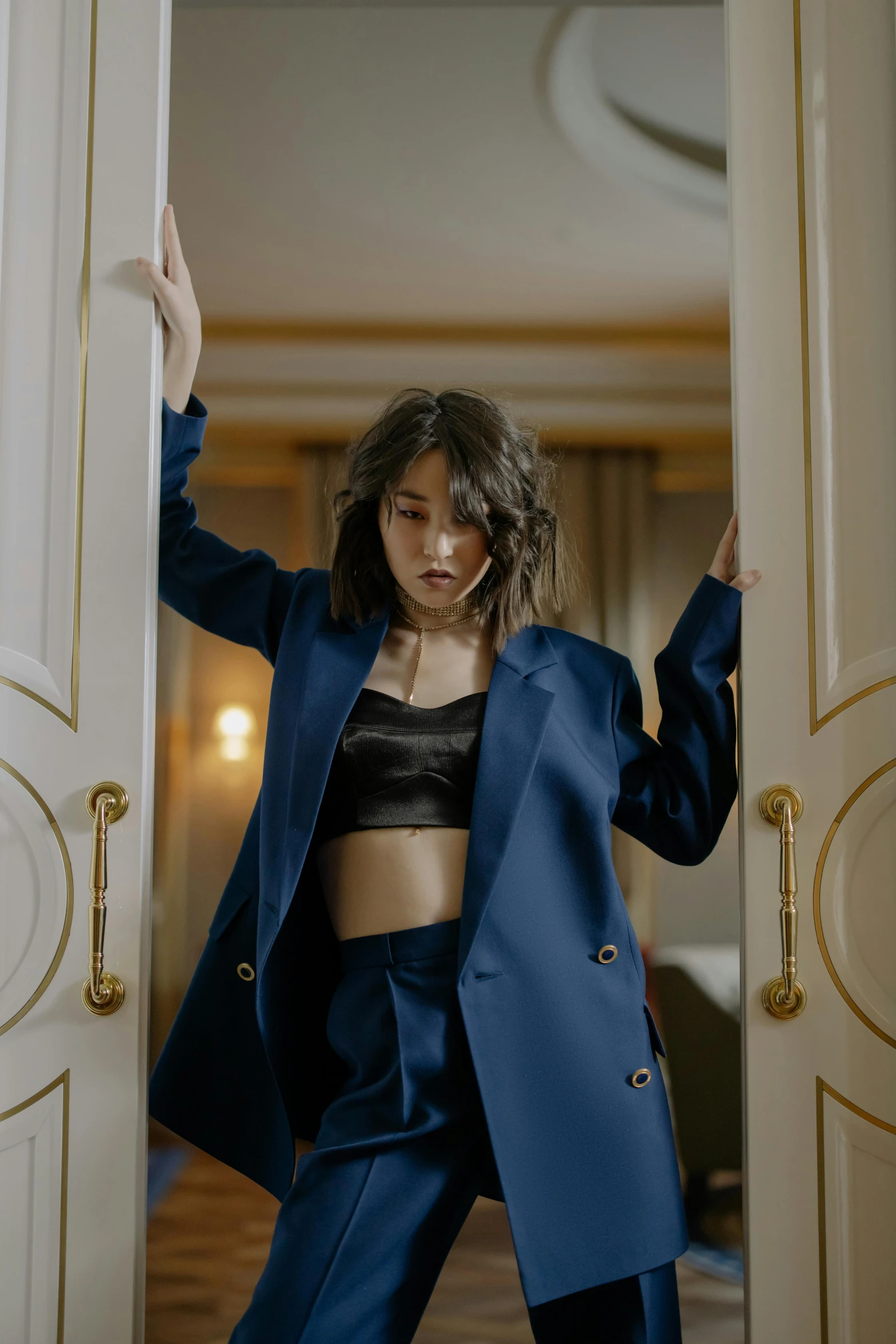 a woman in a blue suit standing in a doorway, trending on pexels, rococo, korean women's fashion model, wearing a crop top, hotel room, leather clothing