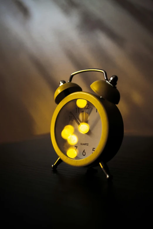 a yellow alarm clock sitting on top of a table, during the night
