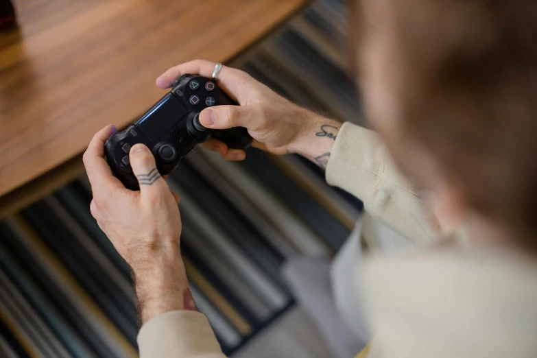 a man holding a video game controller in his hands, by Adam Marczyński, pexels, square enix, hand on table, shot on sony a 7, high quality picture