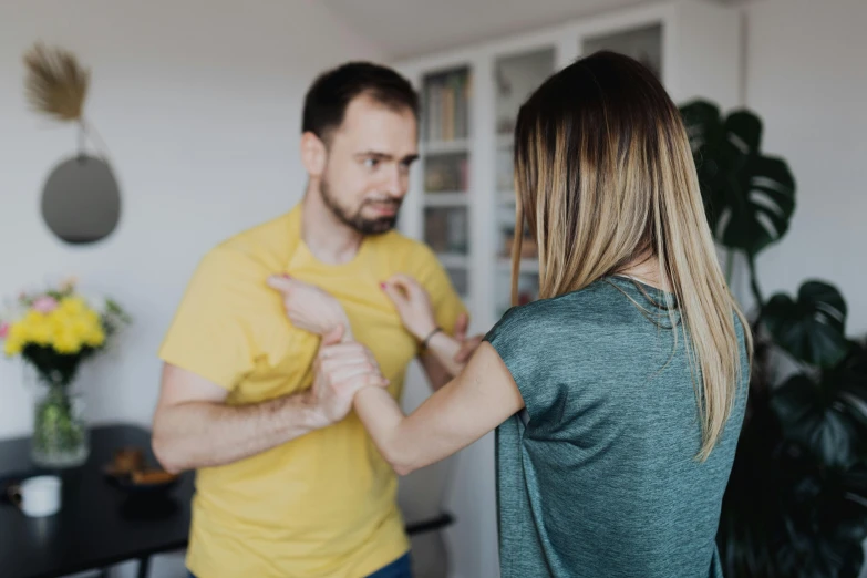 a man standing next to a woman in a living room, by Adam Marczyński, pexels contest winner, bandage taped fists, aggressive stance, profile image, tight around neck