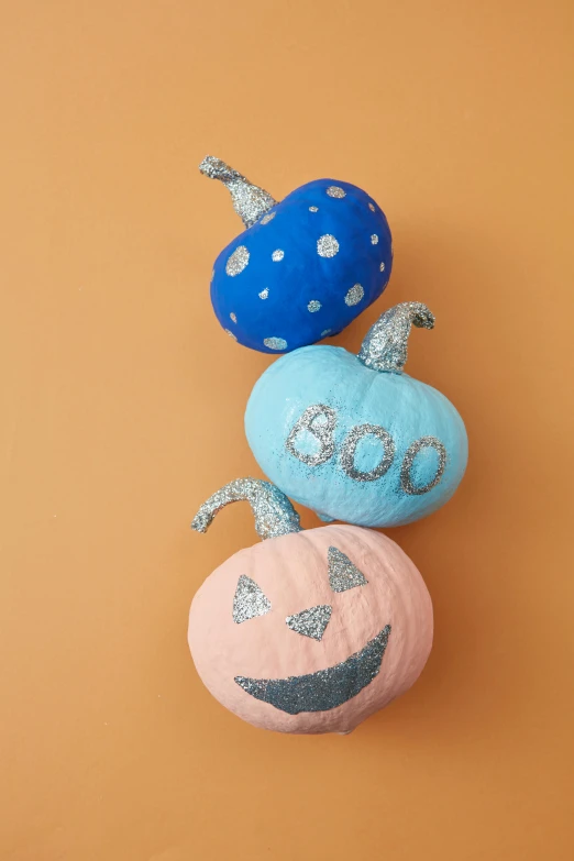 three painted pumpkins sitting on top of each other, sparkling, felt, f / 2 0, goop