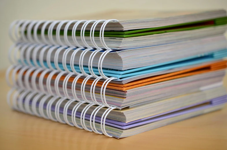a stack of notebooks sitting on top of a wooden table, an album cover, flickr, academic art, vibrant colour, arcs, crisp focus, super detailed image