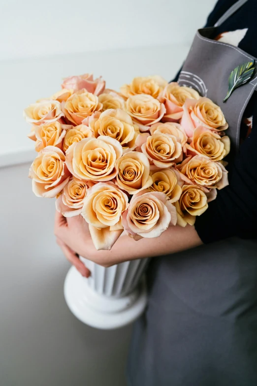 a close up of a person holding a bouquet of flowers, crown of mechanical peach roses, in shades of peach, fan favorite, shades of gold display naturally