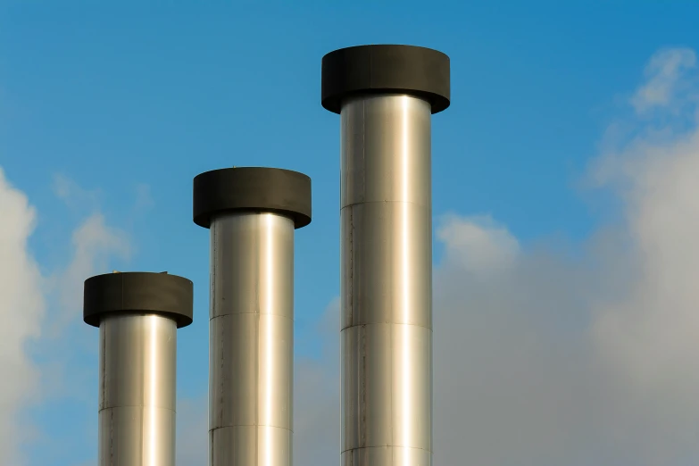 three smoke stacks against a blue sky with clouds, by John Murdoch, unsplash, modernism, with big chrome tubes, pistons and bolts, plain background, foster and partners