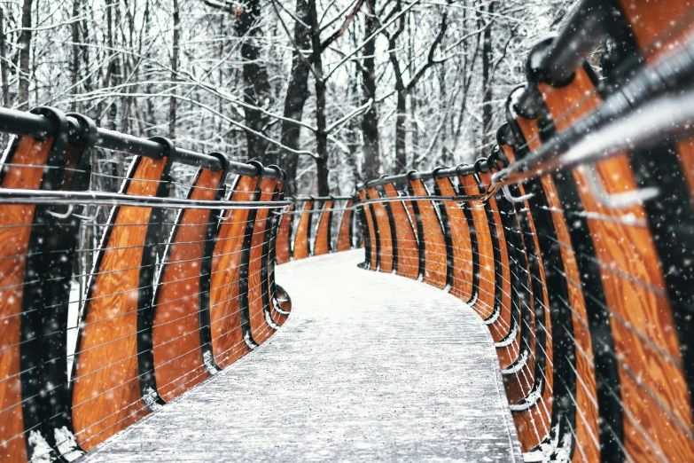 a wooden bench sitting in the middle of a snow covered park, inspired by Christo, unsplash contest winner, graffiti, high bridges, intricate copper details, curving, gray and orange colours