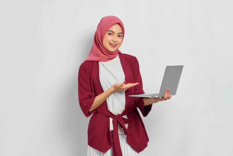 a woman in a hijab holding a laptop, inspired by Nazmi Ziya Güran, hurufiyya, maroon and white, shrugging, slightly minimal, wearing red attire