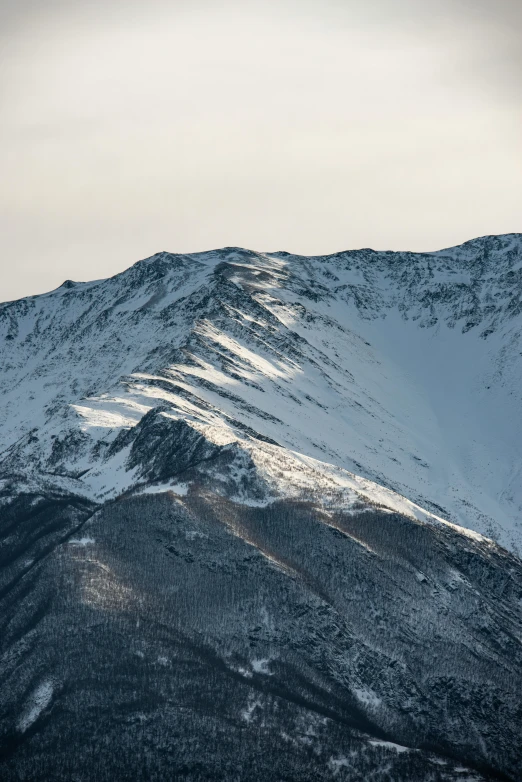 a mountain covered in snow under a cloudy sky, inspired by Tsuji Kakō, trending on unsplash, high detail photo, crater, neck zoomed in, today\'s featured photograph 4k