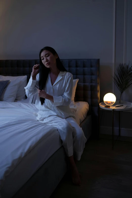 a woman sitting on a bed brushing her hair, inspired by Ruth Jên, minimalism, holding a glowing orb, dim accent lighting, night light, serene bedroom setting