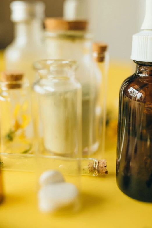 a group of bottles sitting on top of a yellow table, a picture, unsplash, medical labels, natural materials, reagents, vapor