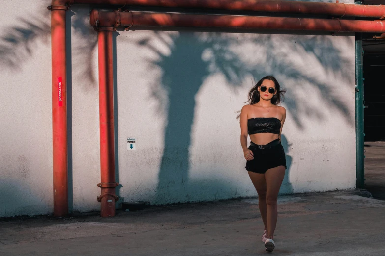 a woman walking down a sidewalk next to a building, pexels contest winner, croptop and shorts, implanted sunglasses, female image in shadow, asian woman