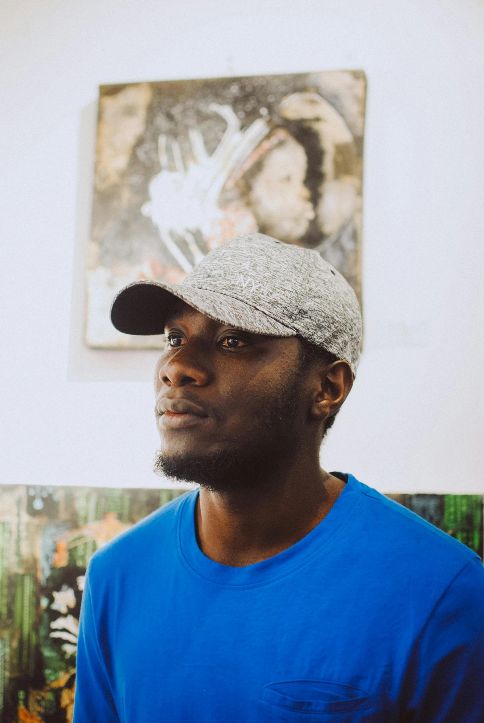 a man standing in front of a painting, an album cover, by Stokely Webster, wearing baseball cap, headshot profile picture, ( ( dark skin ) ), virgil abloh