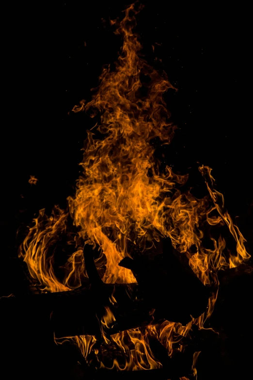 a close up of a fire on a black background, an album cover, pexels, outdoor photo, tall, firey environment, braziers