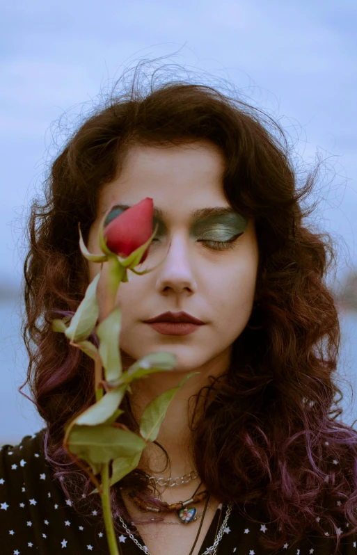 a woman holding a rose in front of her face, an album cover, inspired by Elsa Bleda, trending on pexels, renaissance, curly haired, humanoid flora, icon, looking away