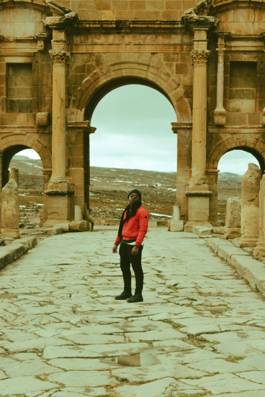 a woman standing in front of a stone arch, an album cover, inspired by ridley scott, pexels contest winner, kurdistan, standing in an arena, tourist photo, casually dressed