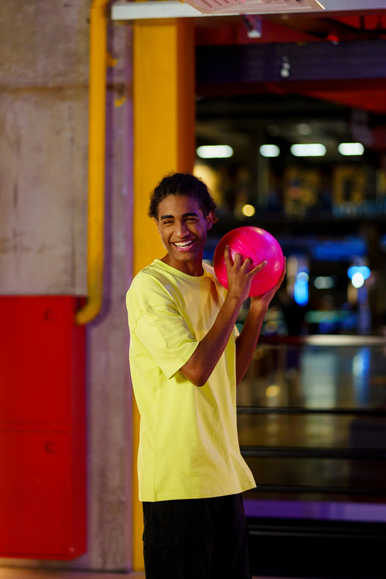 a man holding a pink frisbee in a parking garage, trending on dribble, wearing a modern yellow tshirt, holding a glowing orb, model posing, bowling