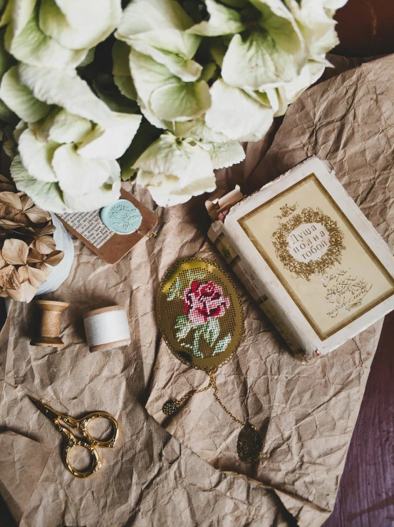 a bunch of flowers sitting on top of a table, a cross stitch, inspired by Eden Box, featured on pinterest, flatlay book collection, ornate gilded details, vintage footage, detailed product image