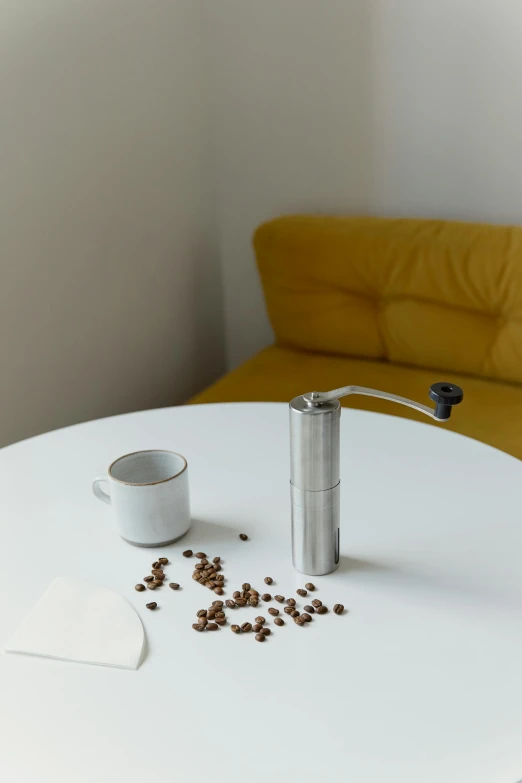 a coffee pot sitting on top of a white table, hand on table, on a table