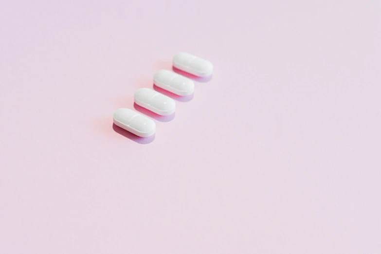 three pills on a pink background, by Emma Andijewska, trending on pexels, antipodeans, lined up horizontally, white colors, in a row, soft white rubber