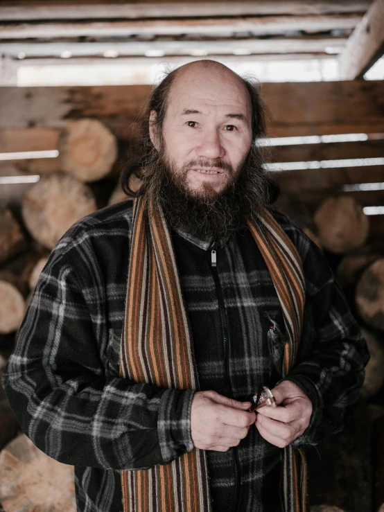 a man standing in front of a pile of logs, a portrait, inspired by Ásgrímur Jónsson, hurufiyya, waxed beard, flannel, maxim sukharev, very slightly smiling