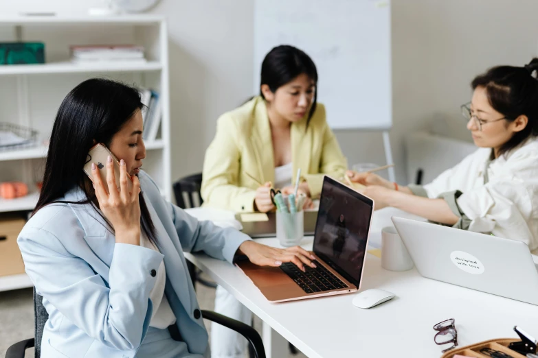 a woman sitting at a table talking on a cell phone, a cartoon, trending on pexels, hurufiyya, coworkers, using a macbook, japanese, mid shot photo