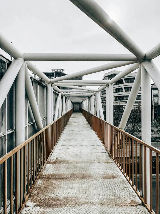 a bridge over a body of water with buildings in the background, inspired by Thomas Struth, unsplash contest winner, brutalism, pathway, detail structure, railing, symmetrical image