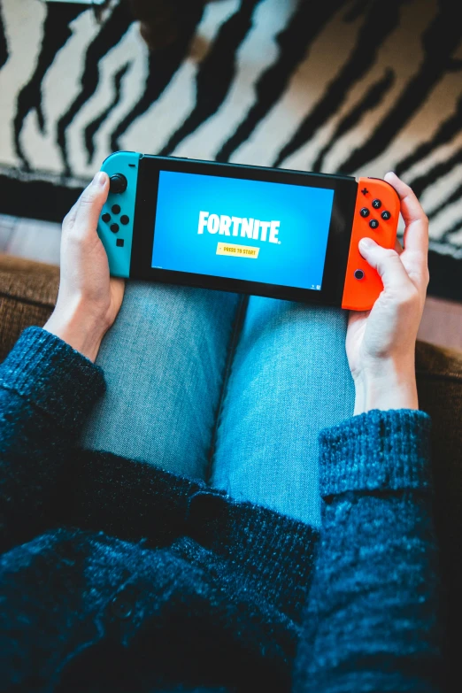 a person sitting on a couch holding a nintendo switch, a cartoon, trending on pexels, in fortnite, 2 5 6 x 2 5 6 pixels, fortninte, gaming table