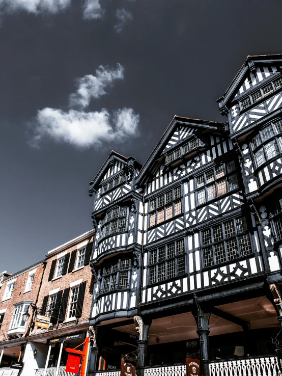 a group of people walking down a street next to tall buildings, by IAN SPRIGGS, unsplash, arts and crafts movement, timbered house with bricks, black and whitehighly detailed, square, coventry city centre