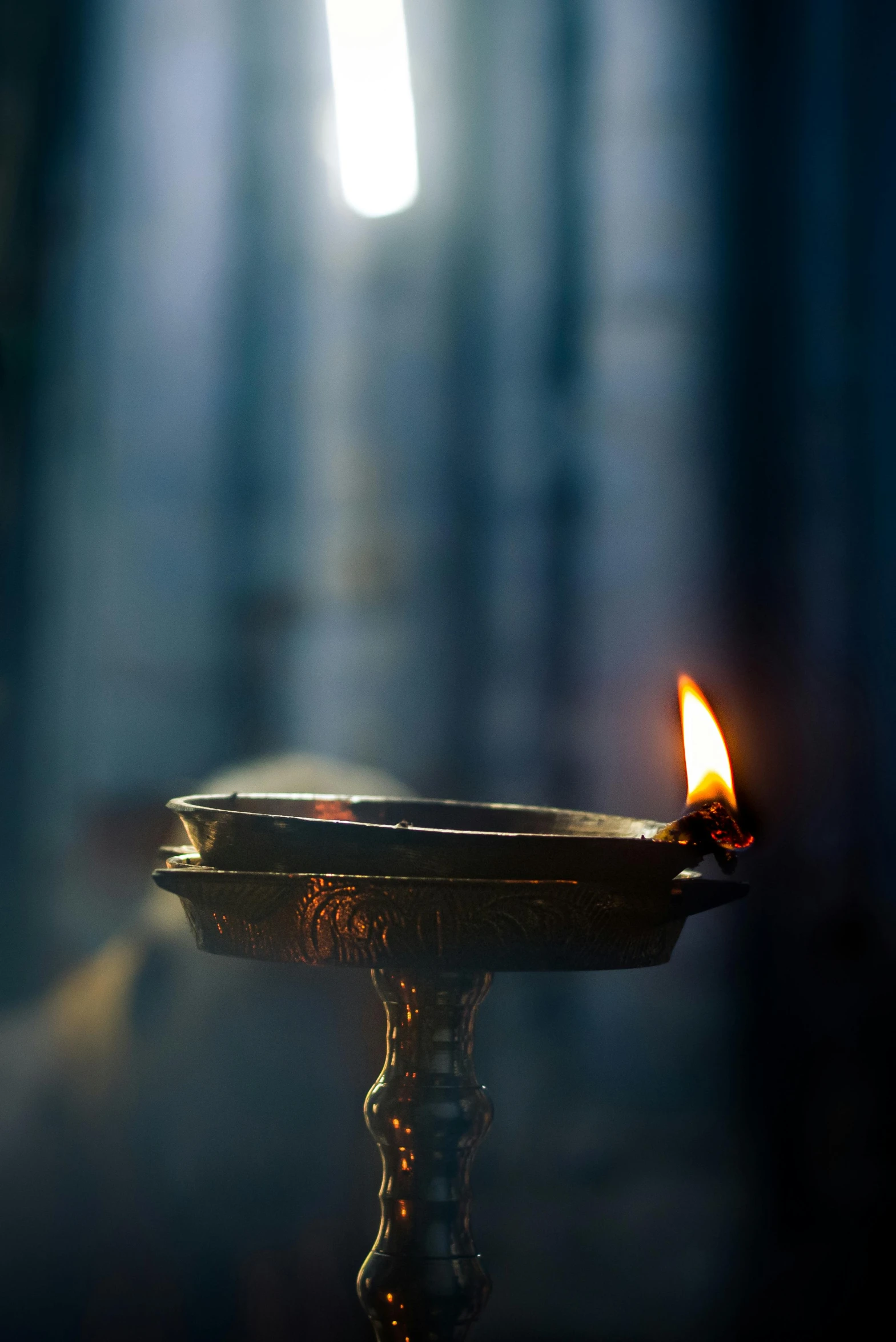 a candle is lit in a dark room, pexels contest winner, light and space, indian temple, morning sunlight, blue flame, grey