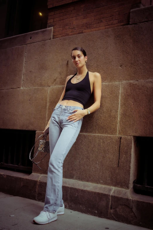 a woman leaning against a wall with a tennis racket, by Nina Hamnett, pexels contest winner, jeans pants, bella poarch, in new york, wearing : tanktop