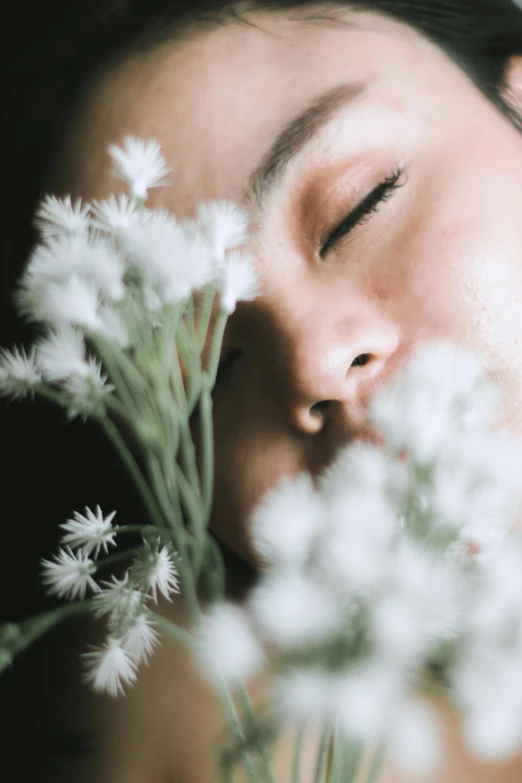 a close up of a person holding a bunch of flowers, inspired by Elsa Bleda, trending on unsplash, romanticism, eyes closed, gypsophila, an asian woman, dreaming face